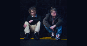 Tom George Fletcher and Ruari Spooner sit side by side on a kerb in a promotional image for Charles My Dear Friend